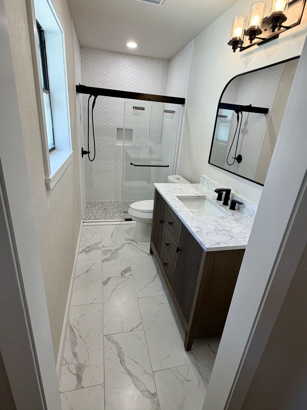 Remodeled bathroom with walk-in glass shower and quartz vanity